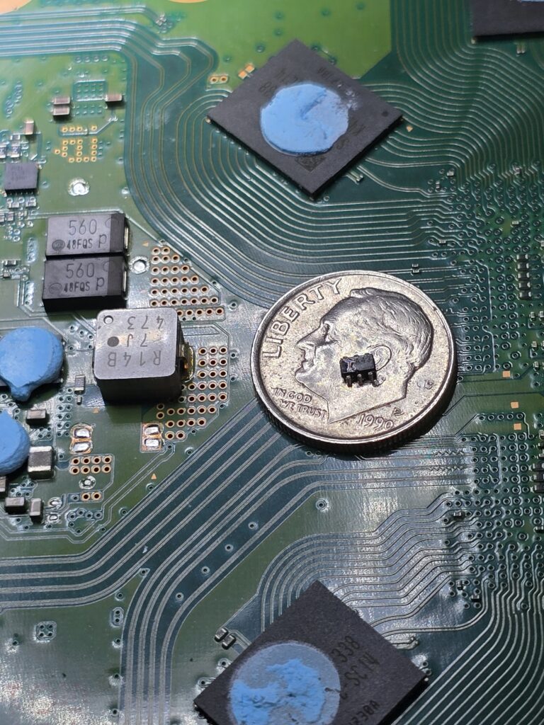 Failed PS5 HDMI power switch IC shown on top of dime for size comparison, causing a no-video boot issue before micosoldering repair at iFix 757 in Virginia Beach.